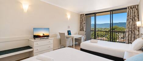 A hotel room with a bed, a desk, a chair, a TV, and a balcony with a view.