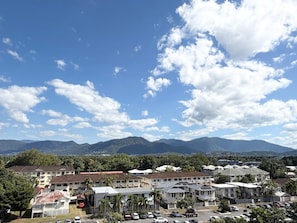 A residential area with multiple buildings, a parking lot, and mountains in the background. - The Oceanfront Cairns (Cairns)