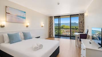 Une chambre d’hôtel avec un lit, un bureau, une télévision et un balcon offrant une vue.