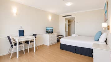 Una habitación con cama, escritorio, silla y un cuadro en la pared.