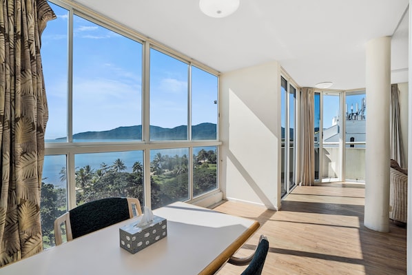 A room with large windows, a table with a tissue box, and a chair.