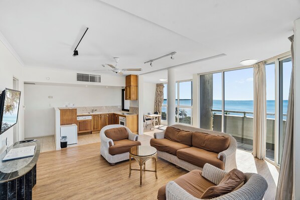 A spacious living area with a balcony, a kitchen, and a dining area.