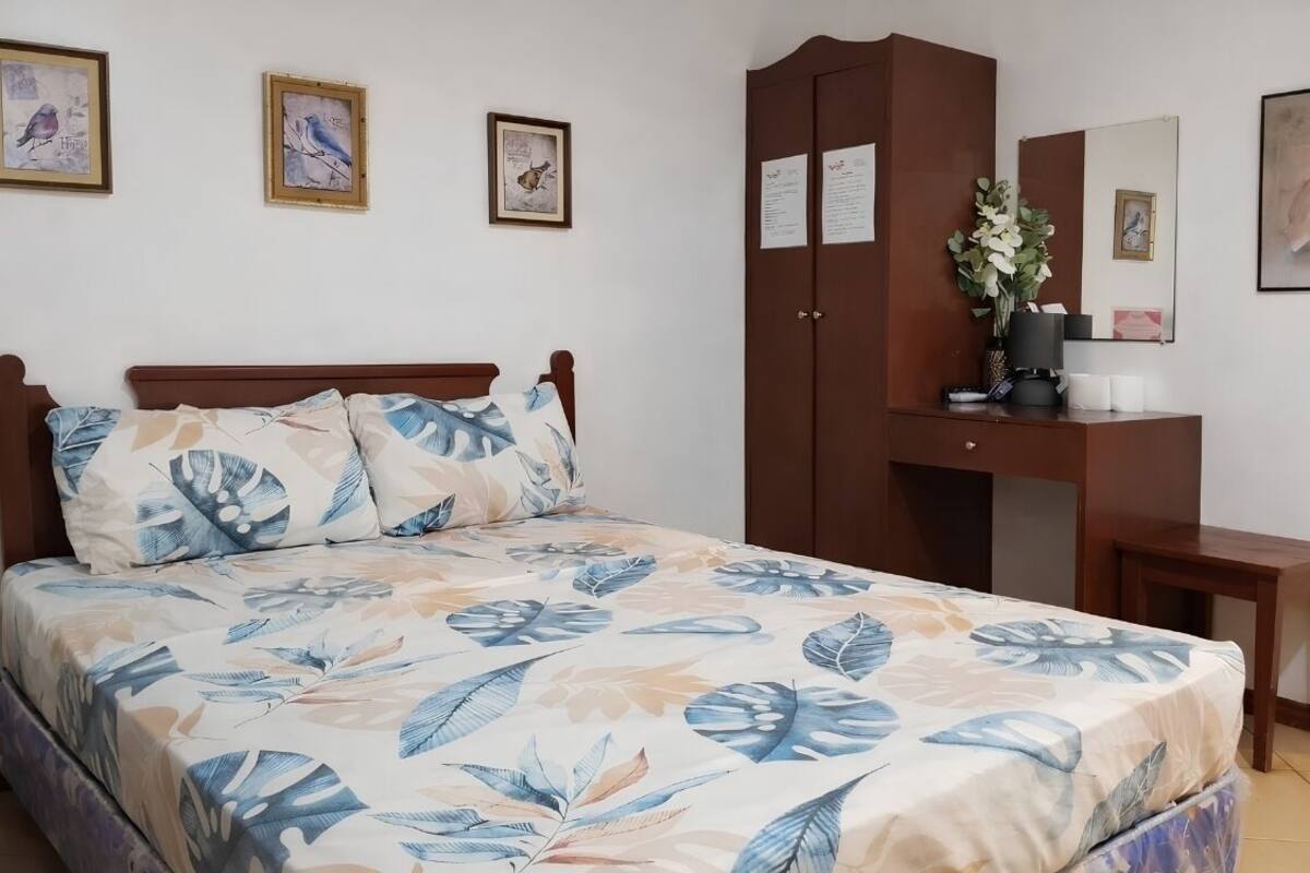 Un dormitorio con cama, armario, escritorio y espejo.