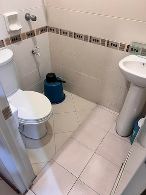 Un baño pequeño con inodoro, lavamanos y calentador de agua azul.
