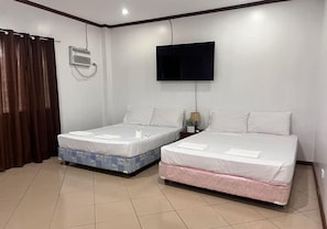 Une chambre dâhĂŽtel avec deux lits, un tĂ©lĂ©viseur, un appareil de climatisation et un rideau.