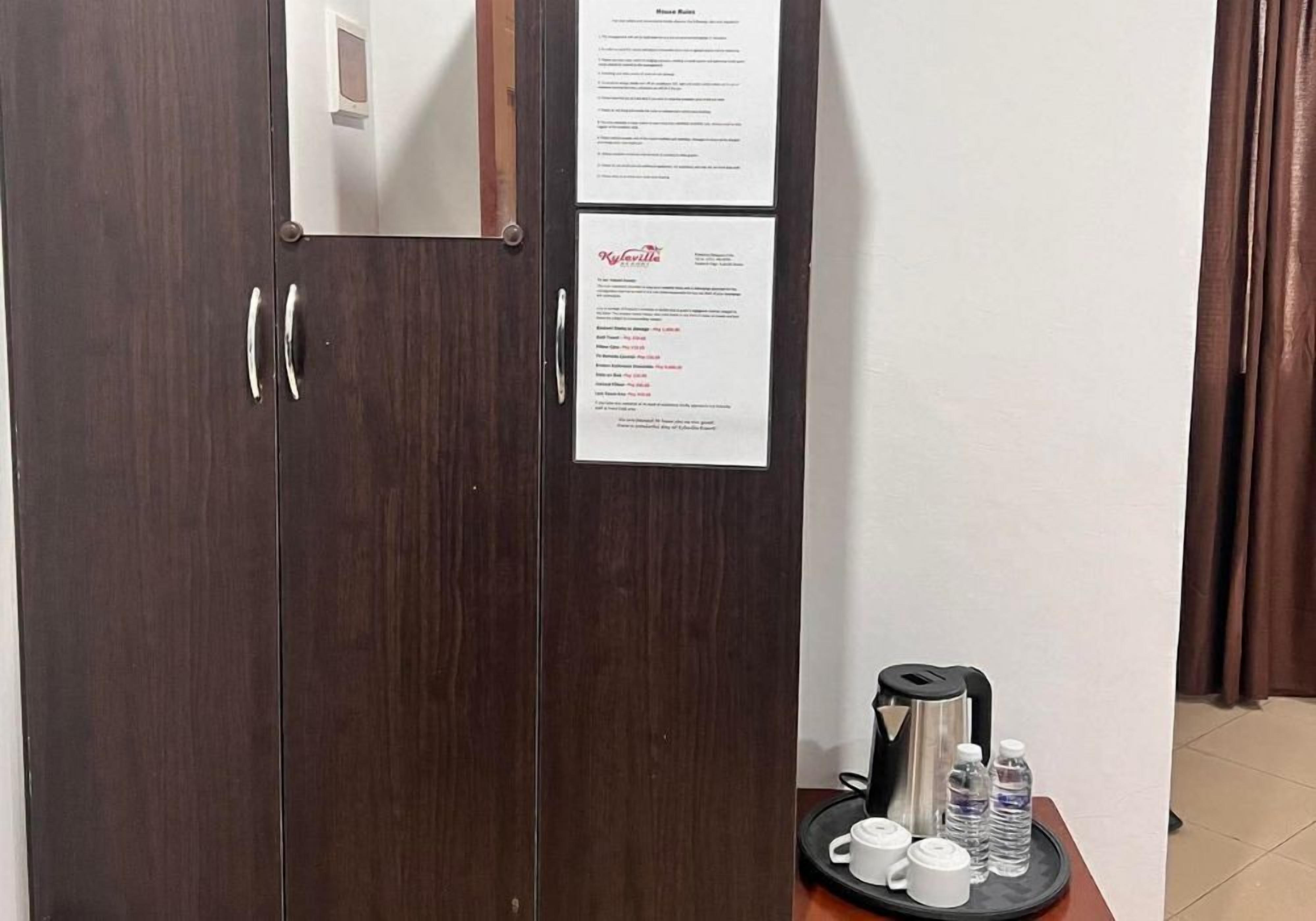 Un armario de madera oscura con dos puertas, un espejo pequeño y una señal con texto.