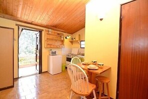 Eine kleine Küche mit Holzschränken, einem weißen Kühlschrank und einem Essbereich mit Holztisch und Stühlen.