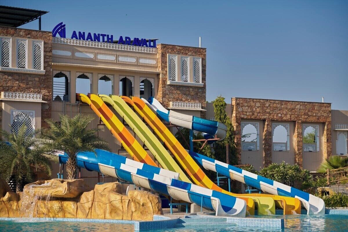 Un parque acuático con múltiples toboganes frente a un edificio con el nombre 'Ananth ARVATI'.