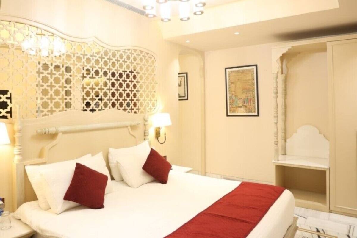 Habitación de hotel con una cama grande, una araña y un armario, además de un detalle decorativo en la pared.
