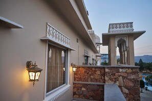 A building with a stone wall, a window with a curtain, and a decorative archway.