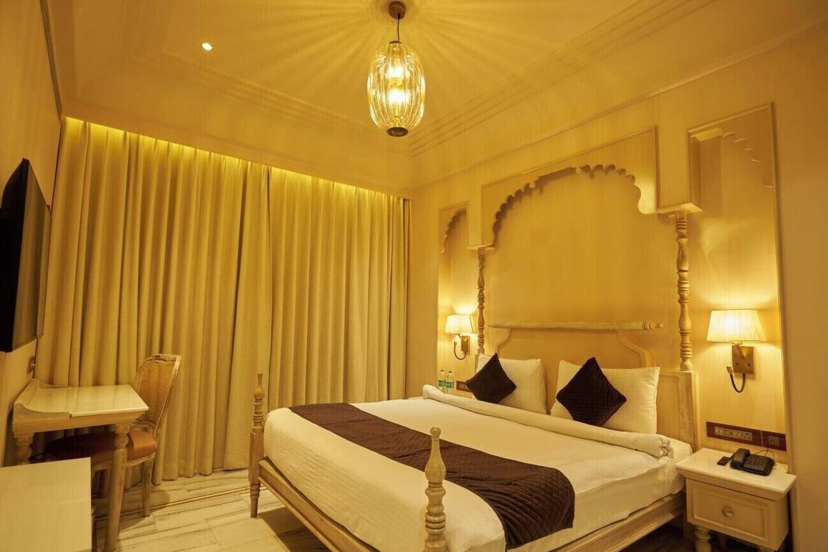 Una habitación de hotel con una cama grande, lámparas de noche, un escritorio y una silla.
