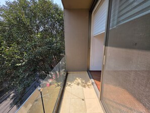 A balcony with a glass door, a tiled floor, and a view of dense foliage. - Modern, luxurious and centrally located minimalist house near the WTC (Del Valle Nte)