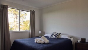 Une chambre d’hôtel avec un grand lit, une table de chevet, une lampe et une fenêtre avec des rideaux.