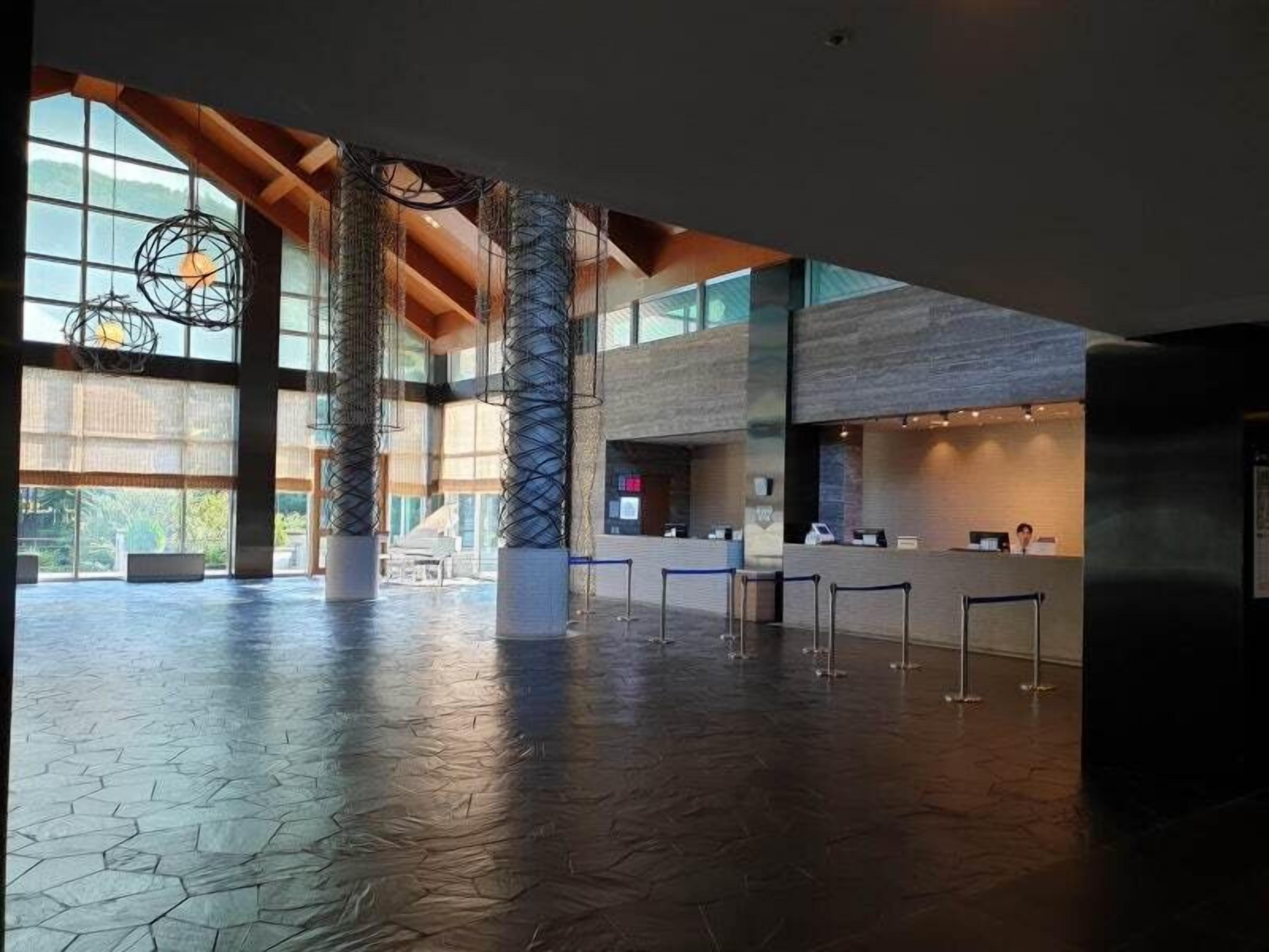 A spacious lobby with high ceilings, large windows, and a reception desk.