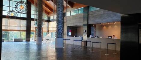 A spacious lobby with high ceilings, large windows, and a reception desk.