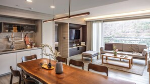 Una cocina moderna con comedor, una sala de estar con sofá y mesa de centro, y un balcón con vistas.