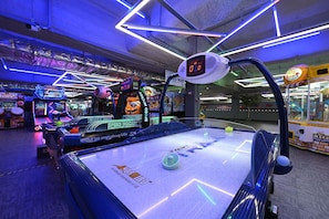 An indoor arcade with various gaming machines, including a speed hockey game and a 3D racing game.