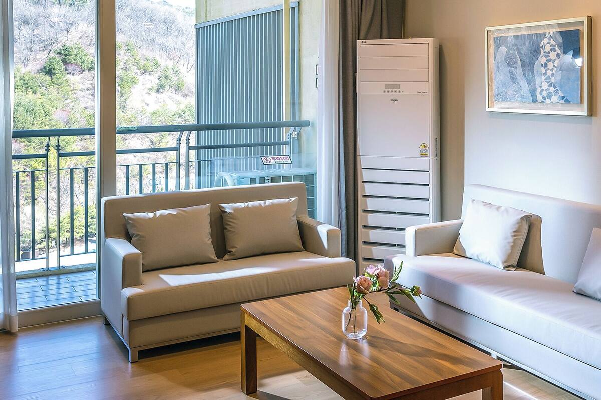 A modern living room with two sofas, a wooden coffee table, and a large window with a view of a mountainous landscape.