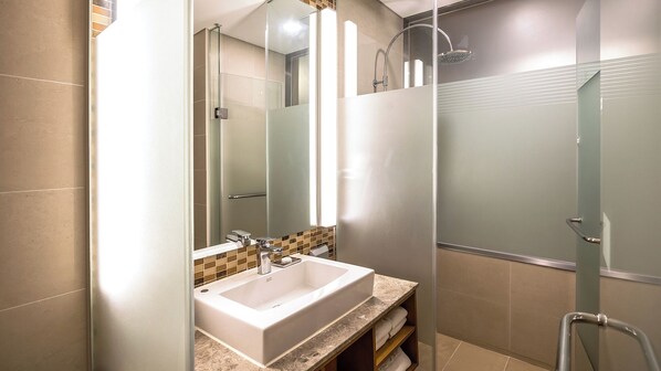 A modern bathroom with a large mirror, a sink, and a shower area.