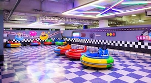 A checkered floor with bumper cars and a wall with 'TUBE BUMPER' signage.