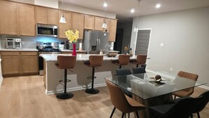 A modern kitchen with wooden cabinets, stainless steel appliances, and a central island with bar stools.