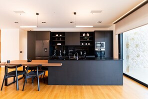 A modern kitchen with a central island, built-in appliances, and a dining area with chairs. - Villa in Corfu with 7 bedrooms sleeps 14 (Corfu)