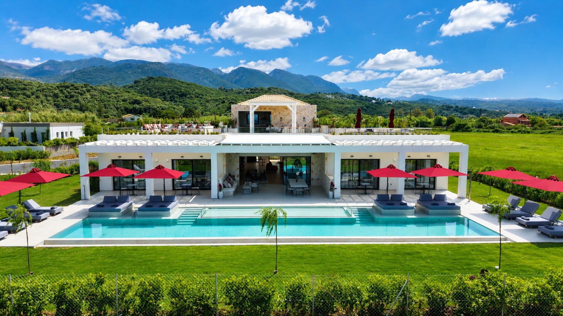 A modern resort with a pool, outdoor seating, and a mountain backdrop.