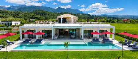A modern resort with a pool, outdoor seating, and a mountain backdrop.