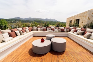 A rooftop terrace with a curved seating area, two round tables, and a view of mountains. - Villa in Corfu with 7 bedrooms sleeps 14 (Corfu)