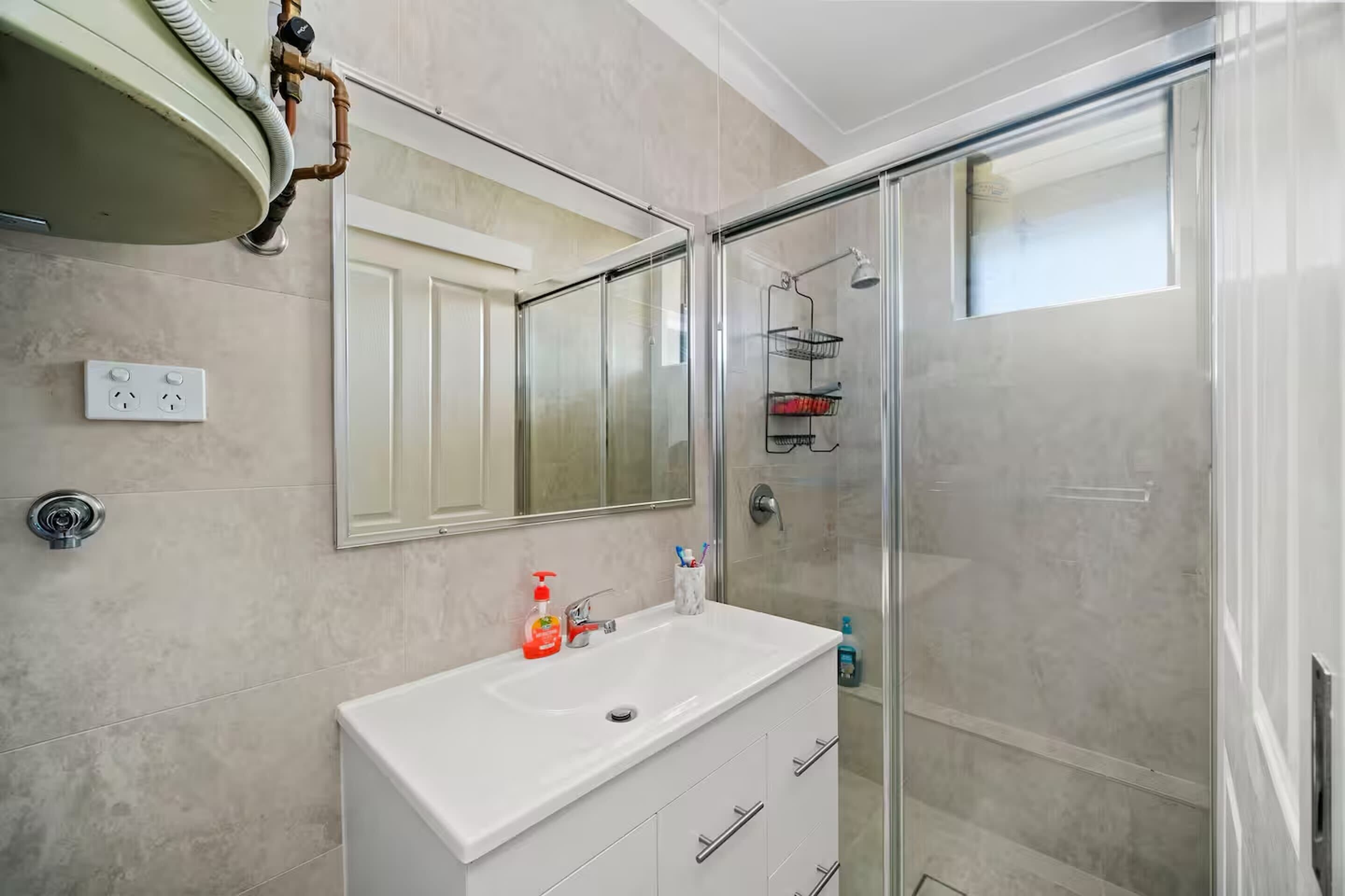 Ein Badezimmer mit Waschbecken, Spiegel und Dusche.