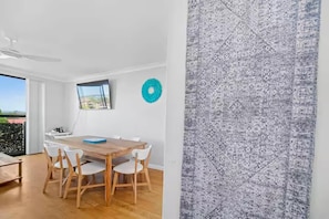 Ein moderner Essbereich mit einem Holztisch, Stühlen, einem Deckenventilator und Blick durch das Fenster.