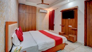 A bedroom with a bed, wardrobe, TV, and ceiling fan. - Hotel Gray Stone (Noida)