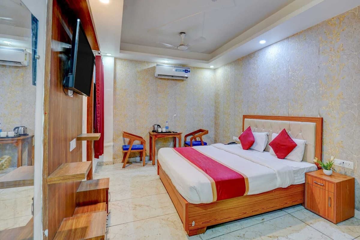 Una habitación de hotel con cama, escritorio, silla, equipo de aire acondicionado y televisor.