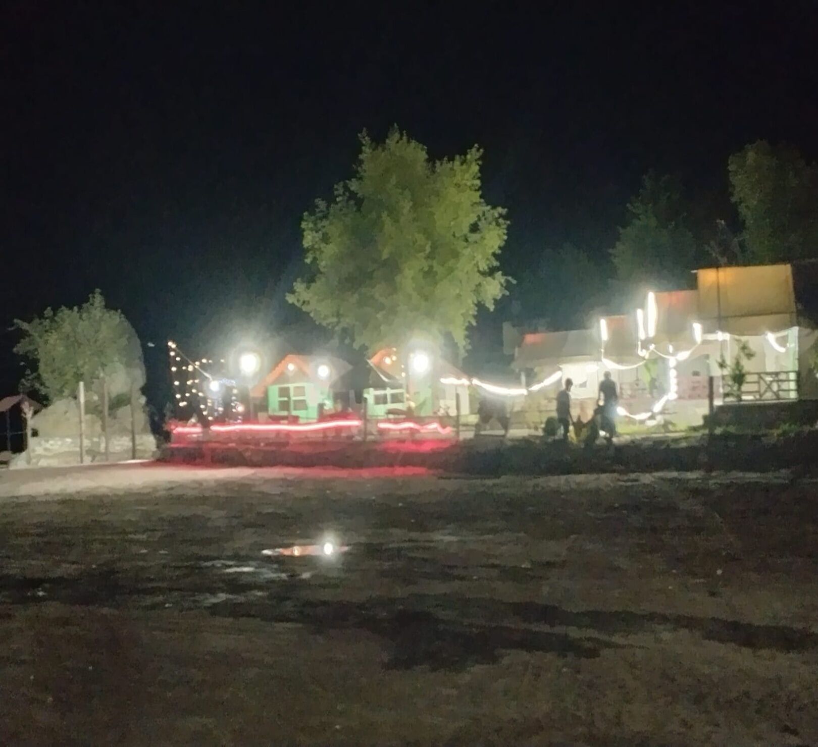 A nighttime outdoor area with illuminated buildings and trees.