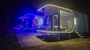 A modern, glass-walled structure with a curved roof, a visible bed, and a small outdoor area. - Oasis Phamee (Ko Pha-ngan)