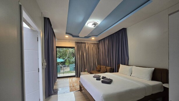 A hotel room with a large bed, a desk, and a view of the outdoors. - Oasis Phamee (Ko Pha-ngan)