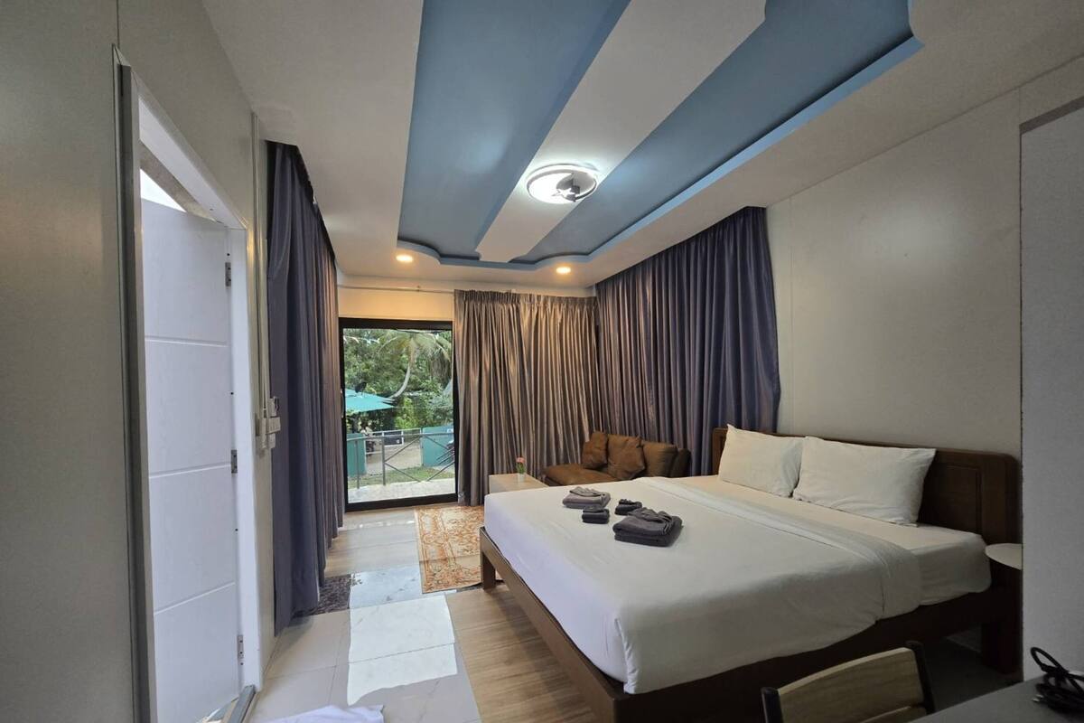 A hotel room with a large bed, a desk, and a view of the outdoors.