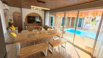 A modern dining area with a wooden table, benches, and a TV mounted on the wall.