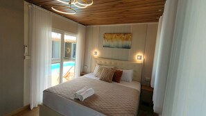 A bedroom with a bed, a painting, and a view of a pool. - 7BR Palm Canopy Pool Villa walk to Lamai Beach (Koh Samui)