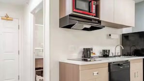 A modern kitchen with a microwave, dishwasher, and a white countertop.