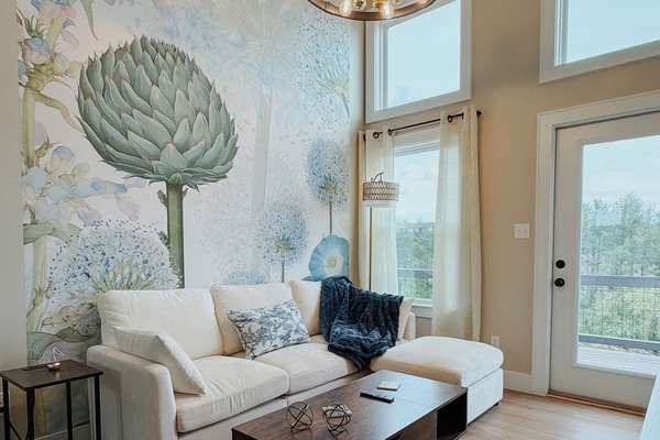 Bright and inviting living space featuring cozy seating, natural light, and a statement mural wall