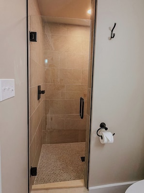 A shower with a glass door, a towel rack, and a toilet paper holder. - Peaceful one-bedroom mountain retreat in Floyd, Virginia featuring a full kitchen, cozy living space, private outdoor seating, and shared fire pit access just minutes from downtown Floyd. (Floyd)