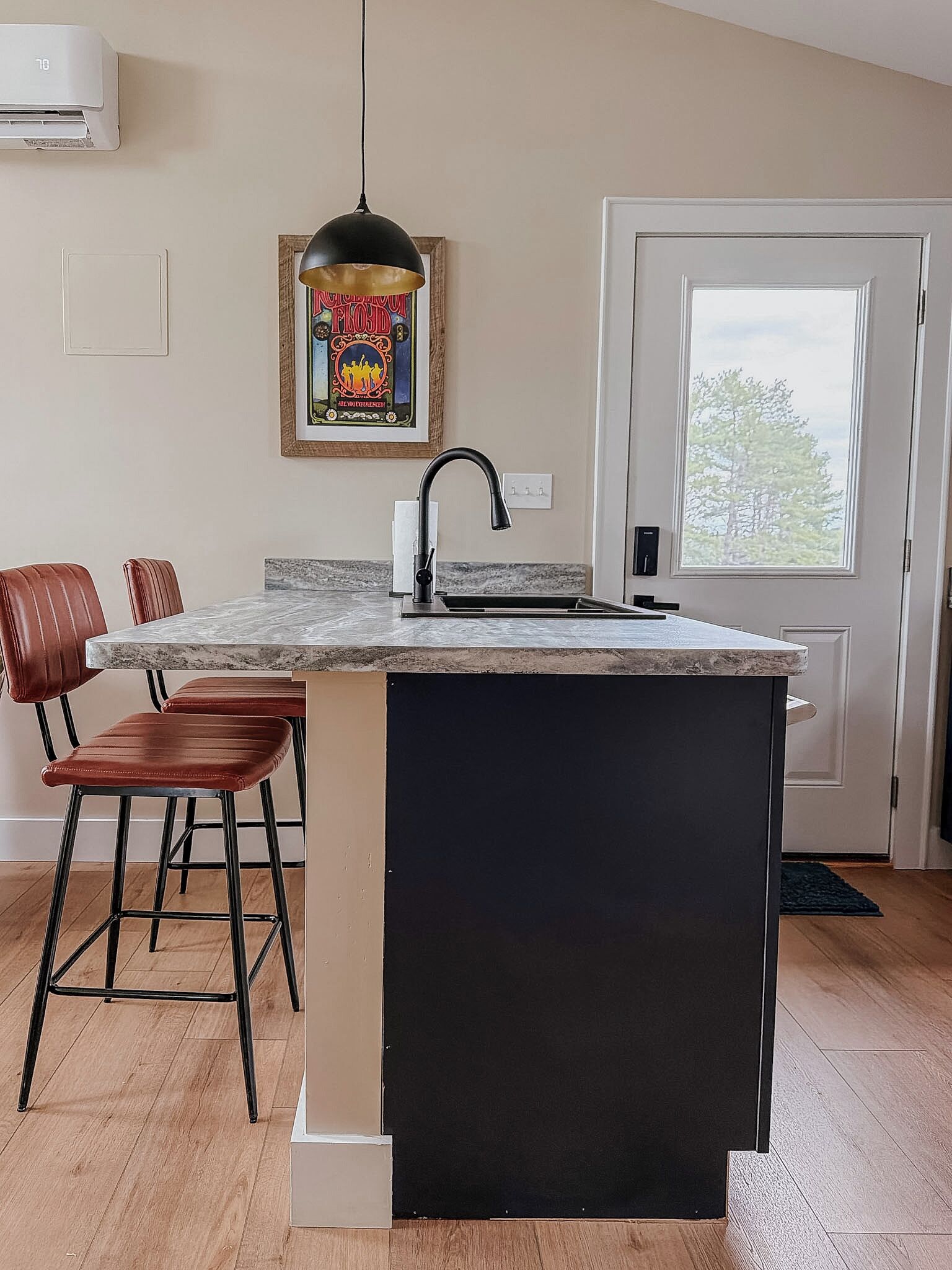 A kitchen with a marble countertop, a black sink, and a pendant light.