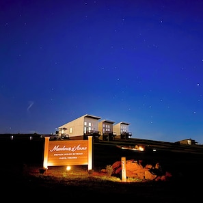 A private retreat with a signboard, a building with multiple levels, and a starry night sky. - Peaceful one-bedroom mountain retreat in Floyd, Virginia featuring a full kitchen, cozy living space, private outdoor seating, and shared fire pit access just minutes from downtown Floyd. (Floyd)