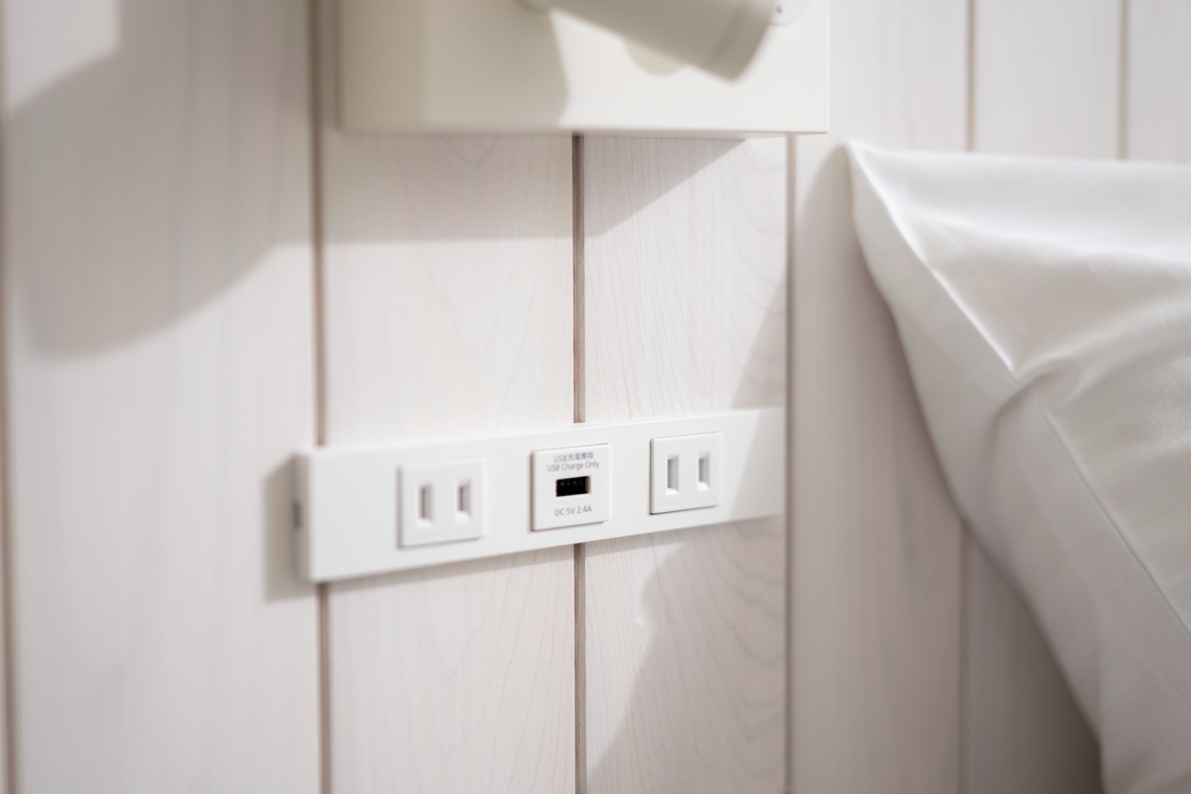 A white wall with a power outlet and a USB charging port.