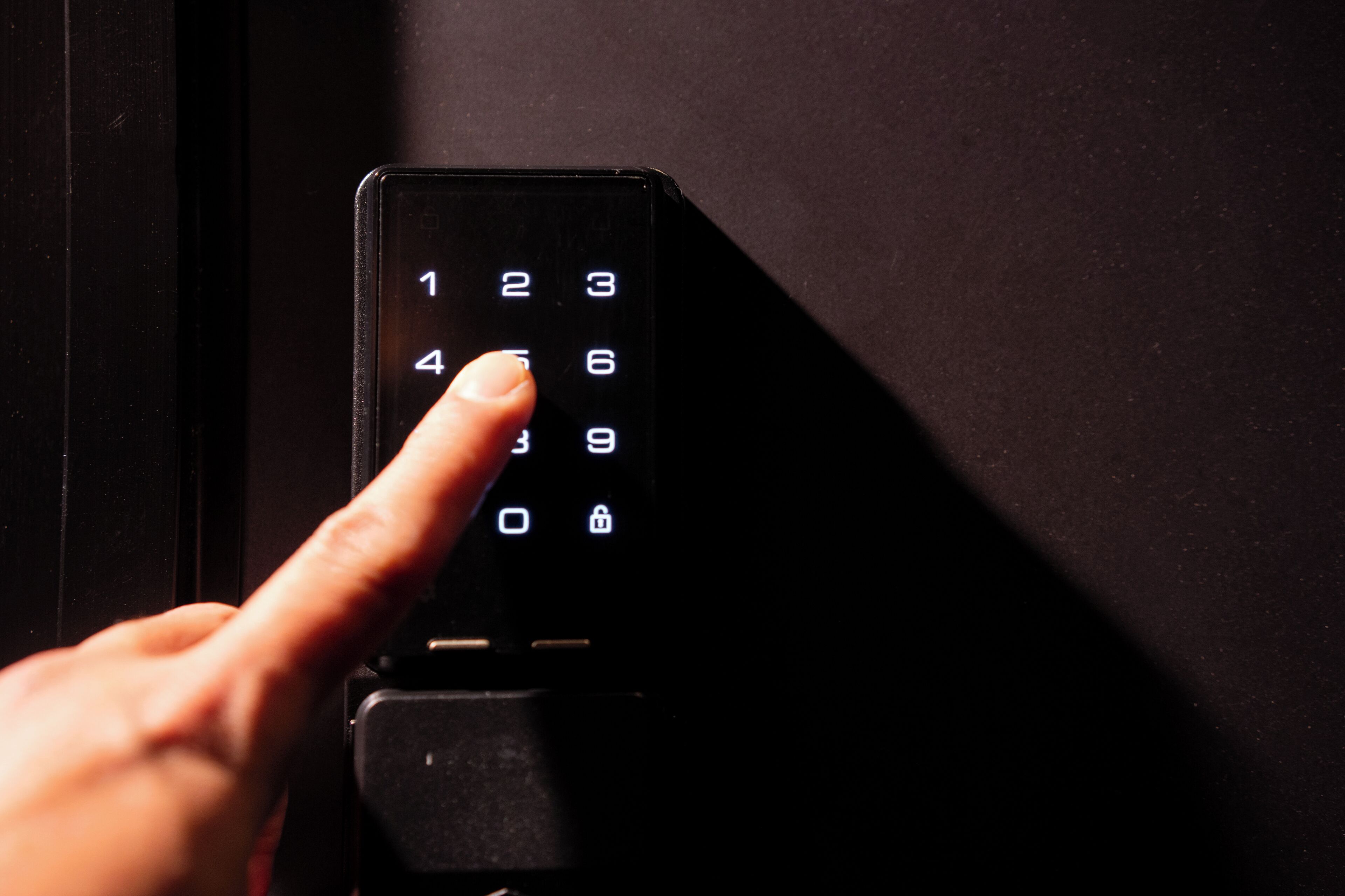 Una mano presionando un teclado numérico en un dispositivo, probablemente un control de acceso o sistema de seguridad.