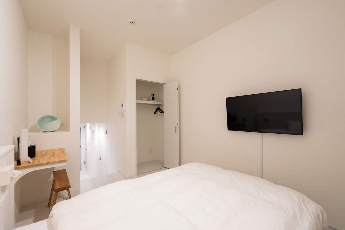 Une chambre à coucher comprenant un lit, un bureau, une chaise, une télévision et une armoire.
