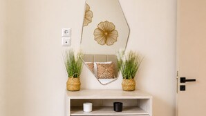 A mirror with a floral design, a woven basket, and a shelf with a white and black mug. - Akrata Comfort Living (Krathi)