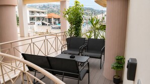 A balcony with a table and chairs, a potted plant, and a view of buildings. - Akrata Comfort Living (Krathi)