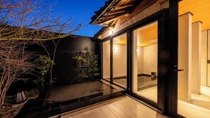 Un edificio moderno con amplias puertas de vidrio, una terraza de madera y una pared exterior oscura.